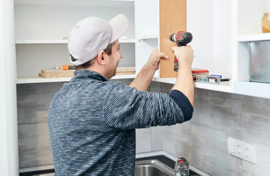 Handyman assembling a wooden cabinet with a power drill in an Austrian home